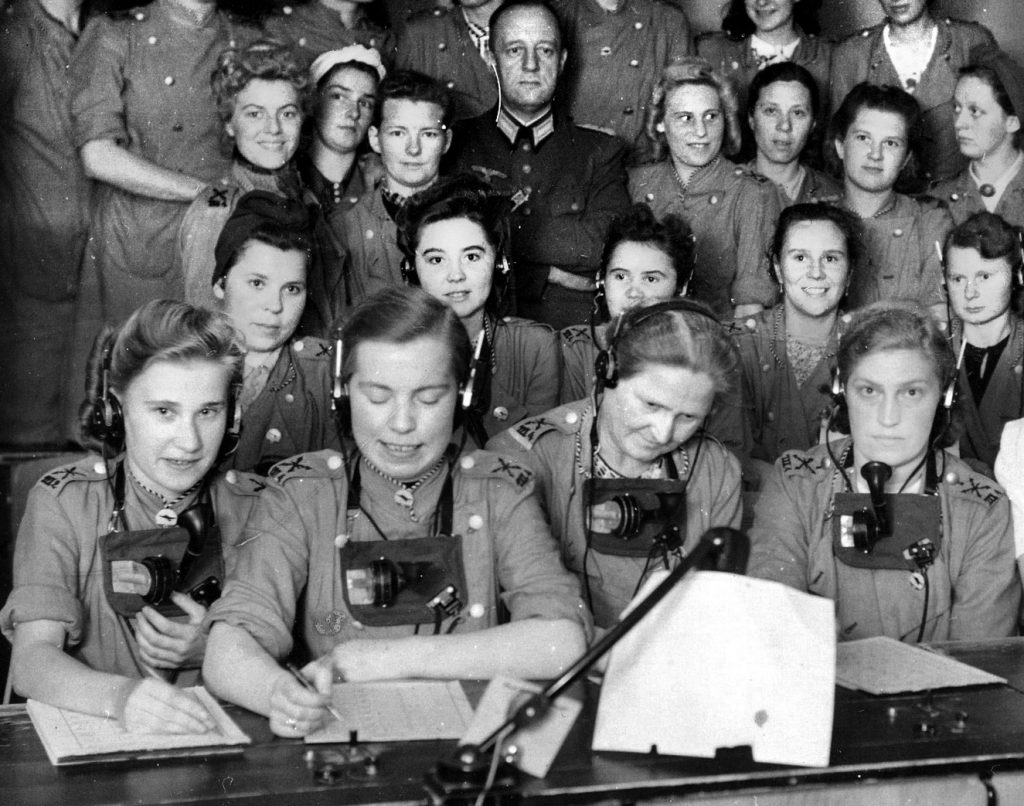 A lone male Army officer is surrounded by a sea of less stern-looking young women.