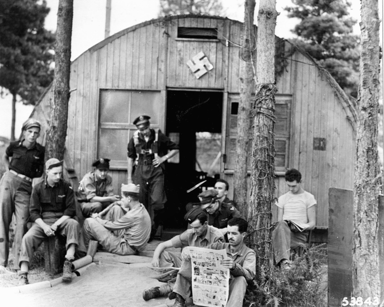 Pilots of the Ninth Air Force fighter group relax outside of the officer’s club at a captured airfield in France. 