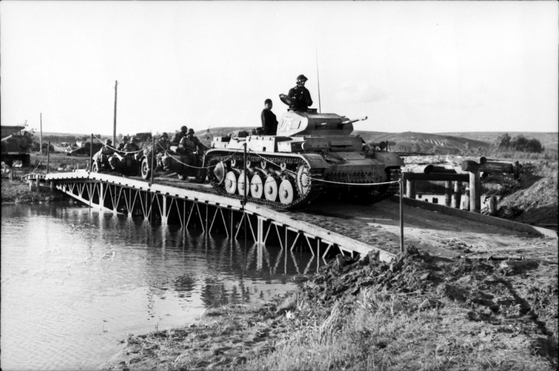 German troops, some riding motorcycles, advance across a makeshift bridge on the route to Voronezh during late June 1942. The tank seen in the photo is the lightly-armed PzKpfw. II, actually obsolete by the time Case Blue was launched.