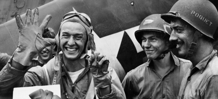U.S. Navy Lieutenant Alex Vraciu holds up six fingers signifying the number of Japanese aircraft that fell to his guns during an eight-minute span on a single mission.