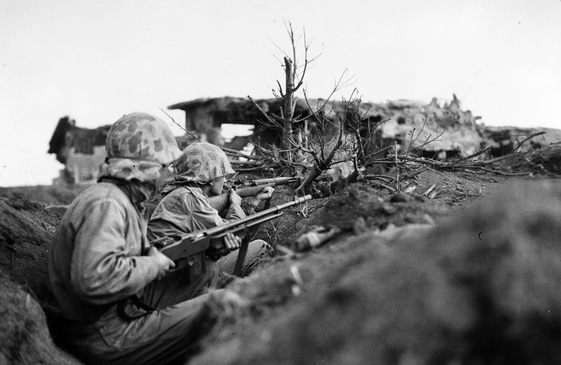 Marines on Iwo Jima take cover from enemy fire near a captured Japanese pillbox. The island had been heavily fortified by the enemy and required 36 days of bitter combat before it was declared secured. INSET: By the time of the Iwo Jima landings, Marine Larry Kirby was a combat veteran.