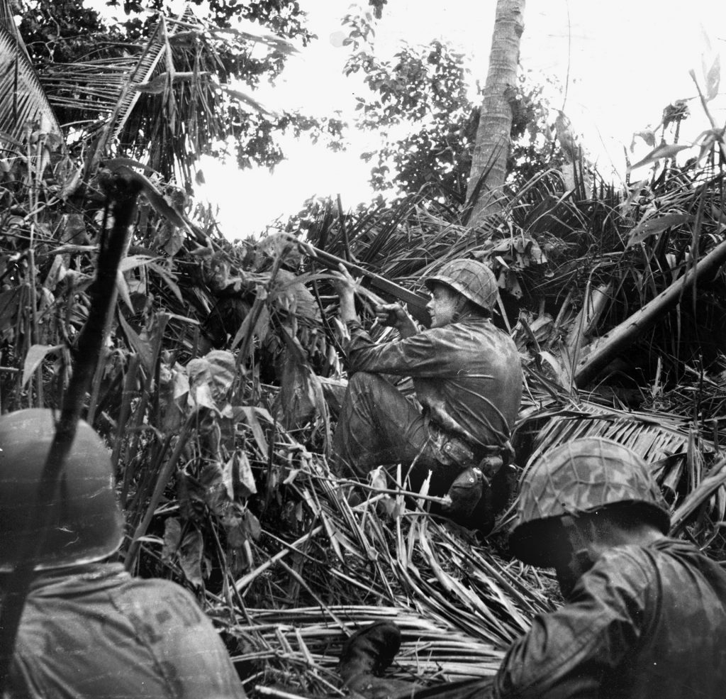 A Marine fires his Thompson submachine gun at a distant enemy target. Kirby carried the Thompson as well, preferring it to the longer stock of the M-1 carbine.