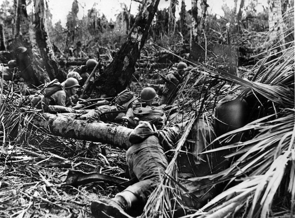 Marines take cover amid debris from the pre-invasion naval bombardment as they move forward during the assault on Guam in the Marianas. Kirby was stunned by the ferocity of a Japanese banzai attack on the island and the resulting carnage. 