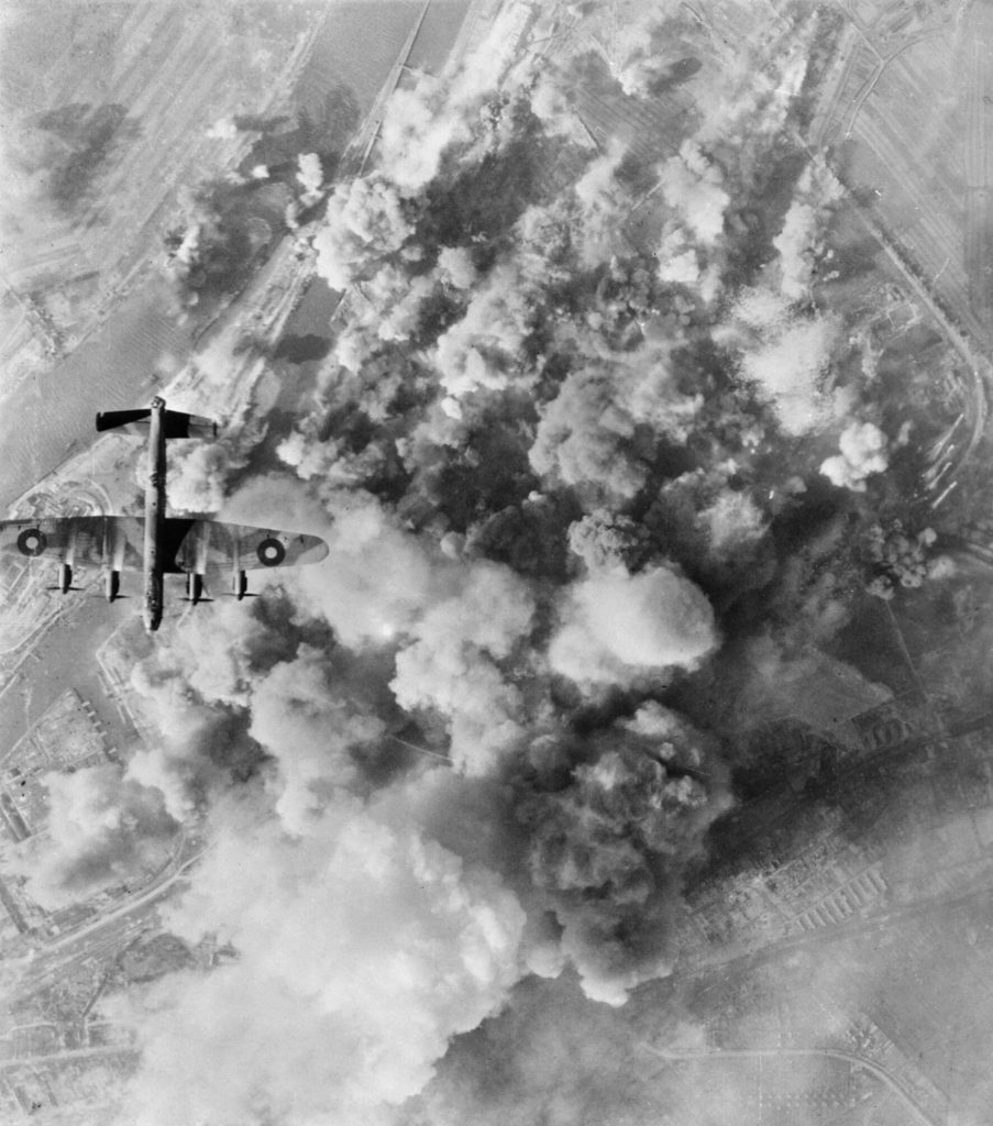 Flying high above the Deutsche Vacuum AG oil refinery and storage depot in Bremen, Germany, an Avro Lancaster of Polish No. 300 Squadron delivers its payload on the smoke obscured target.