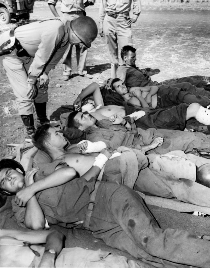 General George Patton, one of his ivory-handled pistols clearly visible at his waist, speaks with wounded soldiers of the U.S. 3rd Infantry Division somewhere in the Mediterranean theater in 1943.