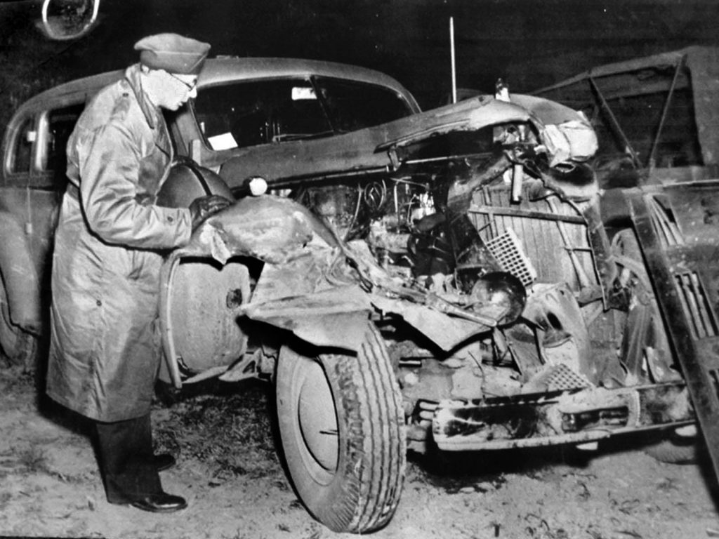 A soldier inspects the damage to the car General Patton was riding in when the accident that  would prove fatal occurred. The damage to the front end of the vehicle was substantial.