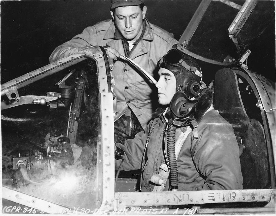 Photographed with his crew chief, fighter pilot Lieutenant Bob ’Swat’ Millikin sits in the cockpit of his Lockheed P-38 Lightning fighter. Millikin was an outstanding pilot and one of the 429th Squadron fliers who became an ace in the skies over Europe.