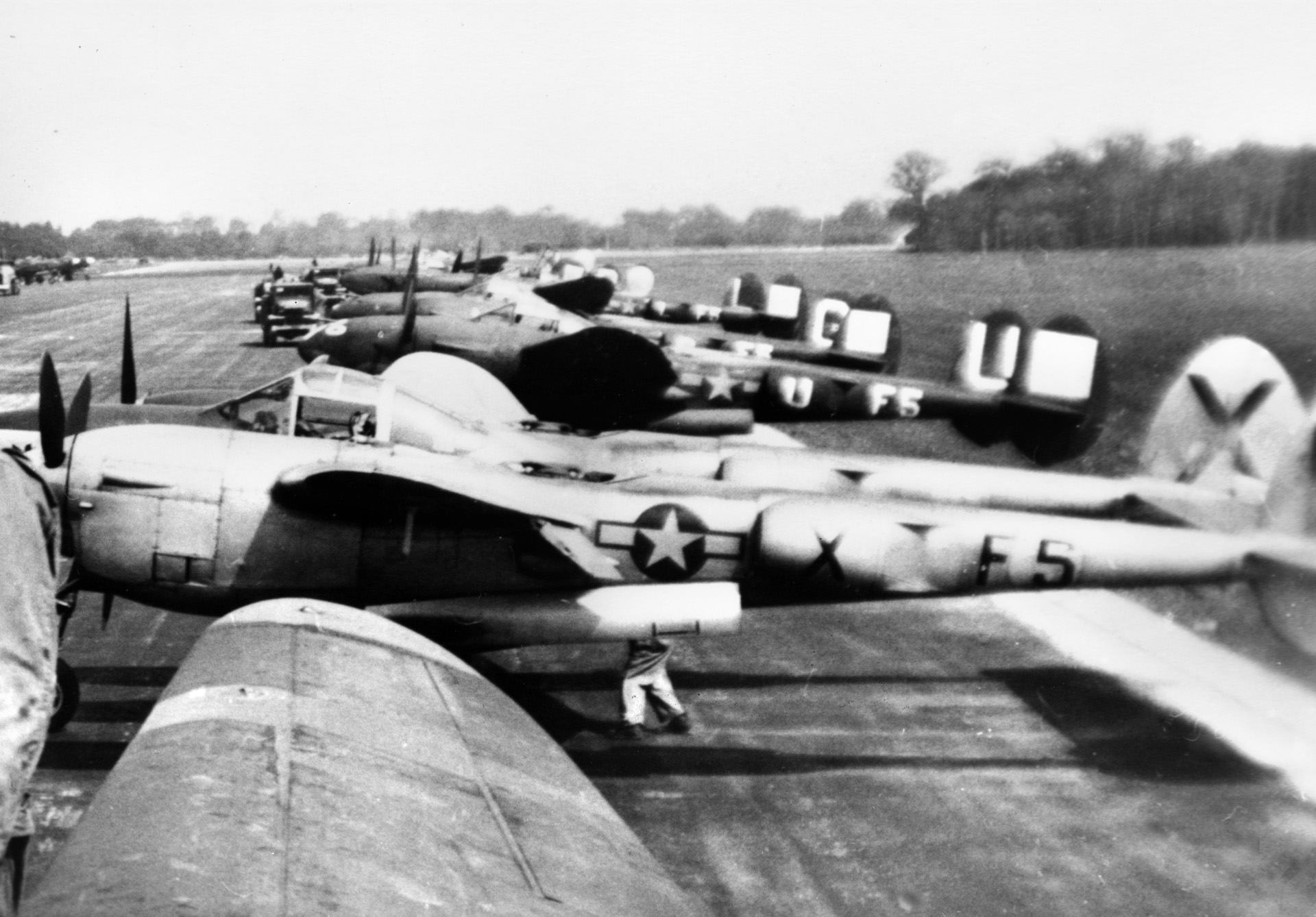 P-38 Lightning fighters of the 428th Fighter Squadron sit tightly grouped at an airfield prior to deployment. These aircraft have not been emblazoned with their D-Day recognition stripes, so this photo was probably taken during the weeks leading up to the June 6, 1944, Normandy invasion at RAF Warmwell airfield in England. 