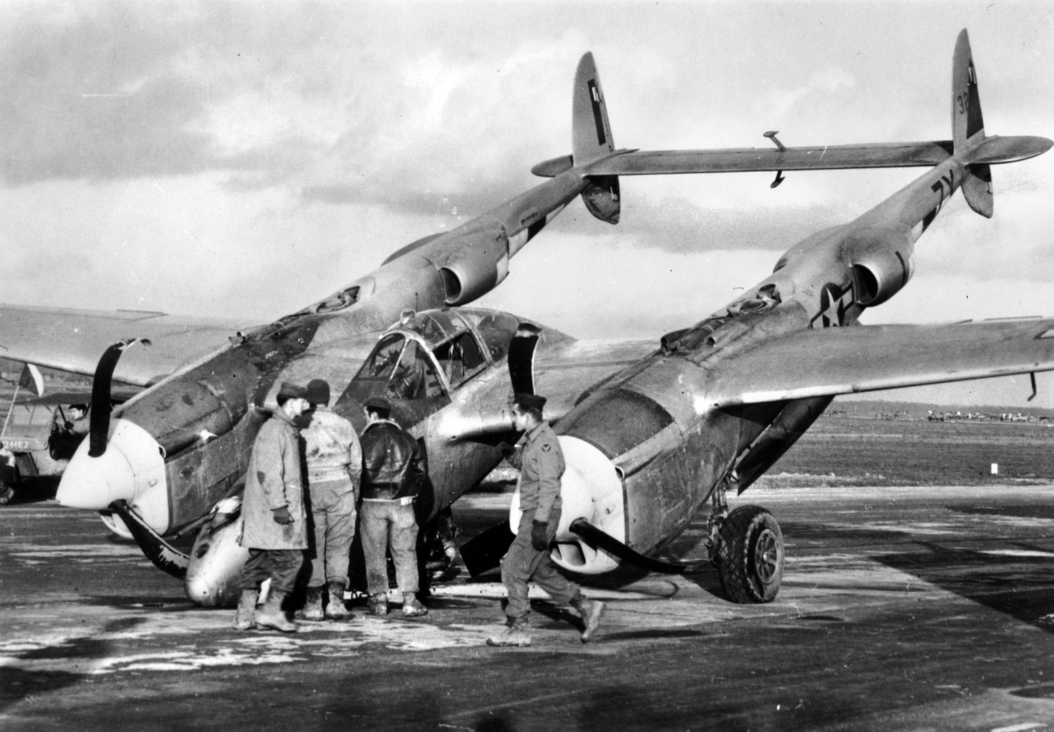 After experiencing a flat tire on landing, this P-38 Lightning fighter of the 429th Fighter Squadron has nosed over. Note the damage to the propellers as American personnel inspect the wreckage. 