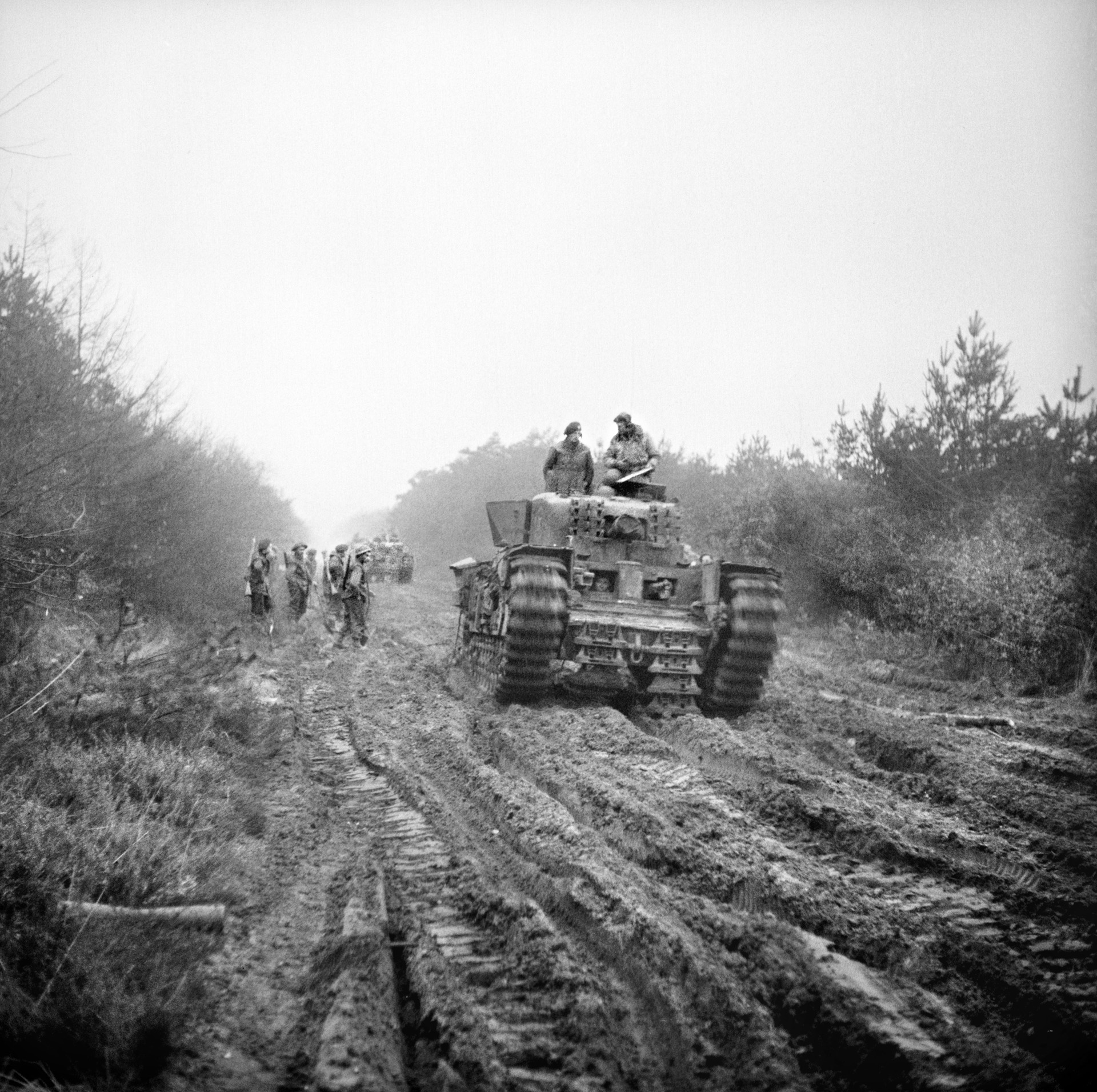 A British Churchill tank powers its way through thick mud along a forest road in the Reichswald at the start of Operation Veritable on February 8, 1945. Behind the tank, sappers of the 45th Division are attempting to strengthen the road, making it more passable for light vehicles.