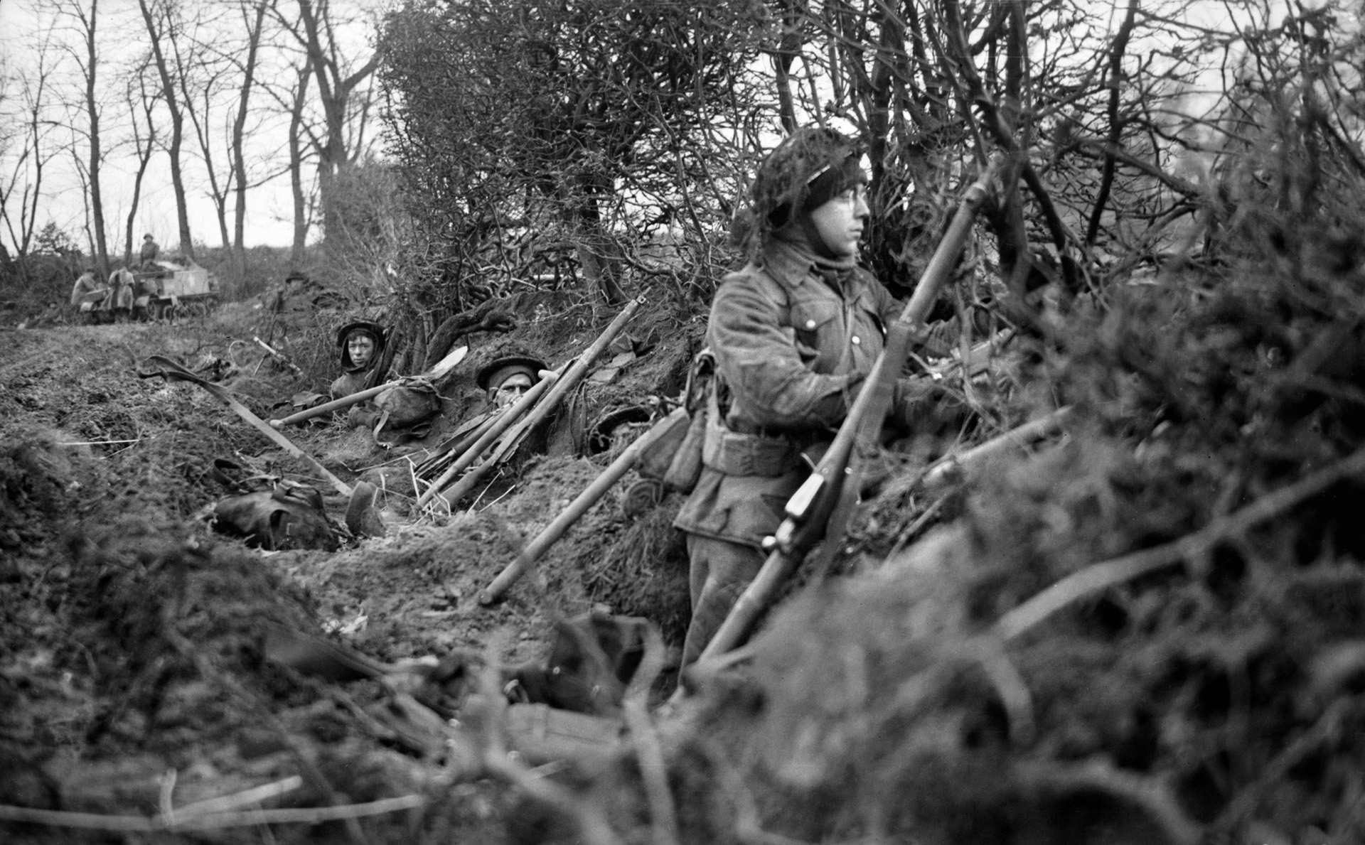 Combat veterans of the 2nd Argyll and Sutherland Highlanders, 15th Scottish Division take temporary shelter along an embankment in the Reichswald.