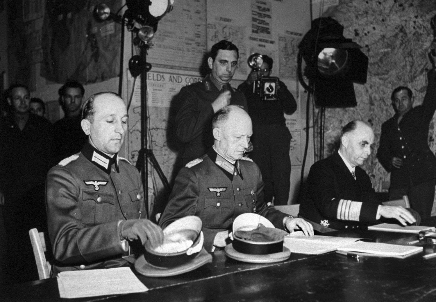 Colonel General Alfred Jodl (center), later convicted and hanged as a war criminal at Nuremberg, prepares to sign the instrument of surrender at General Dwight Eisenhower’s headquarters in Reims, France, at 2:39 AM on May 7, 1945. Major Wilhelm Oxenius and Admiral Hans-Georg Friedeburg are seated to Jodl’s left and right respectively.
