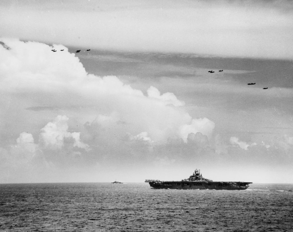 U.S. Navy aircraft fly above the aircraft carrier USS Lexington (CV-16) on June 20, 1944, during an attempted Japanese air attack west of Guam. These warships and aircraft belong to Task Group 58.3.  They include <a href=