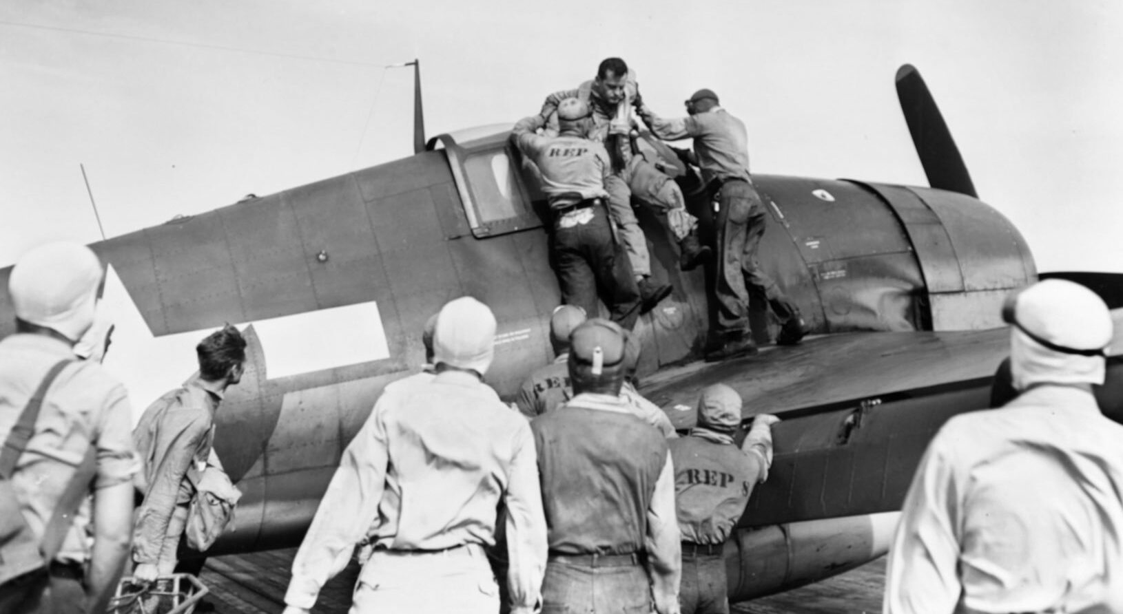 The pilot of a U.S. Navy Grumman F6F Hellcat fighter is assisted from the cockpit of his plane after a mission.  American fighters shot down so many Japanese planes that one pilot dubbed the affair the ‘Great Marianas Turkey Shoot.’