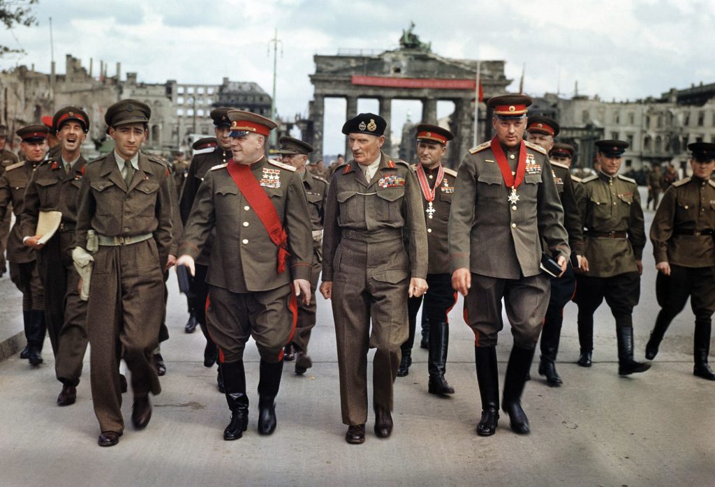 British Field Marshal Bernard Montgomery (center) walks with Marshal Georgi Zhukov (left) and Marshal Konstantin Rokossovsky (right) following ceremonies in Berlin in July 1945. The famous Brandenburg Gate, scarred by recent fighting, stands in the background.