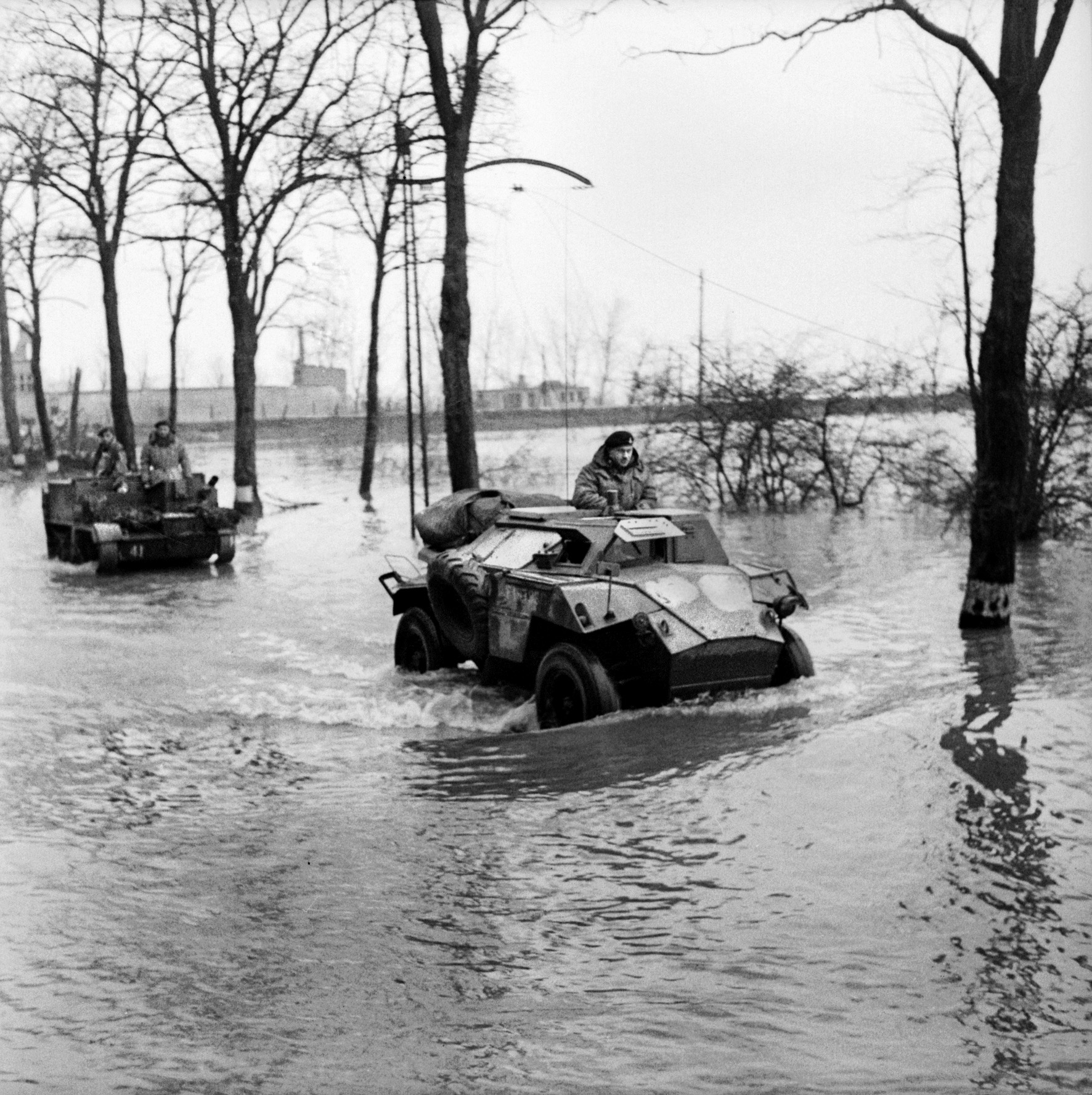 A British Humber scout car and a universal carrier splash across the flooded landscape near the towns of Beek and Kranenburg in Germany. 