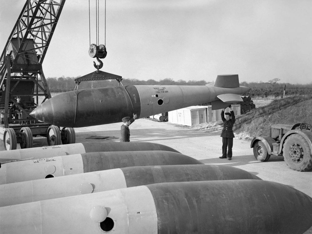 The imposing size of the Tallboy bomb is revealed in this image of RAF personnel maneuvering one of them into storage with the assistance of a crane.