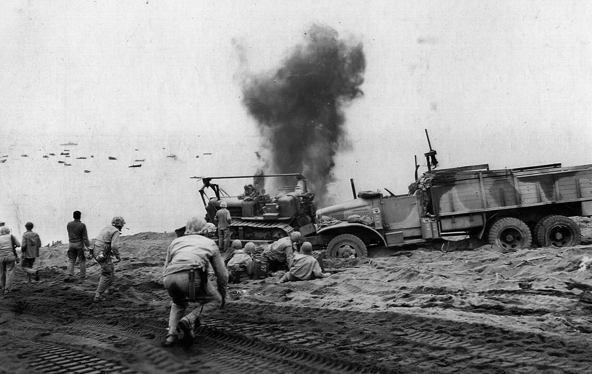 Smoke and debris fill the air behind a demolition squad as they comb the beach for Japanese booby traps. 