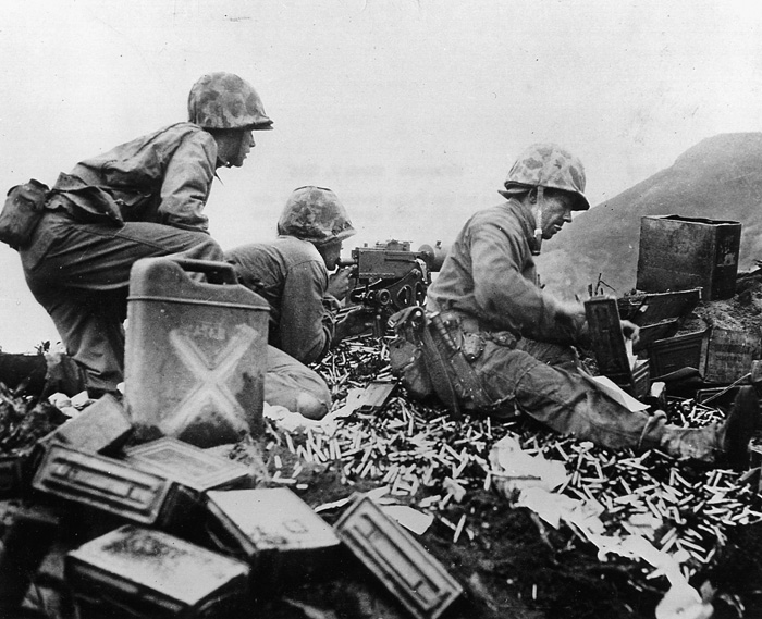 Surrounded by spent shell casings, a group of Marines man a .50-caliber machine-gun nest and scan the horizon for signs of attacking Japanese. 