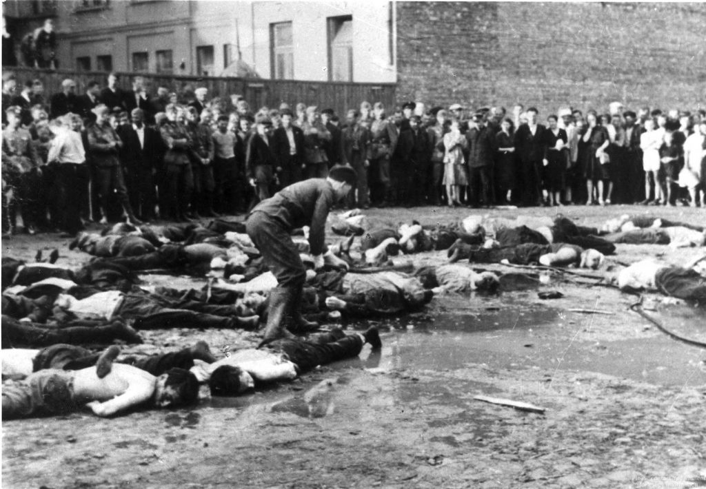 Encouraged by German soldiers, pipe-wielding Lithuanian criminals attack Jews in Kaunas, Lithuania, as civilians and soldiers look on.
