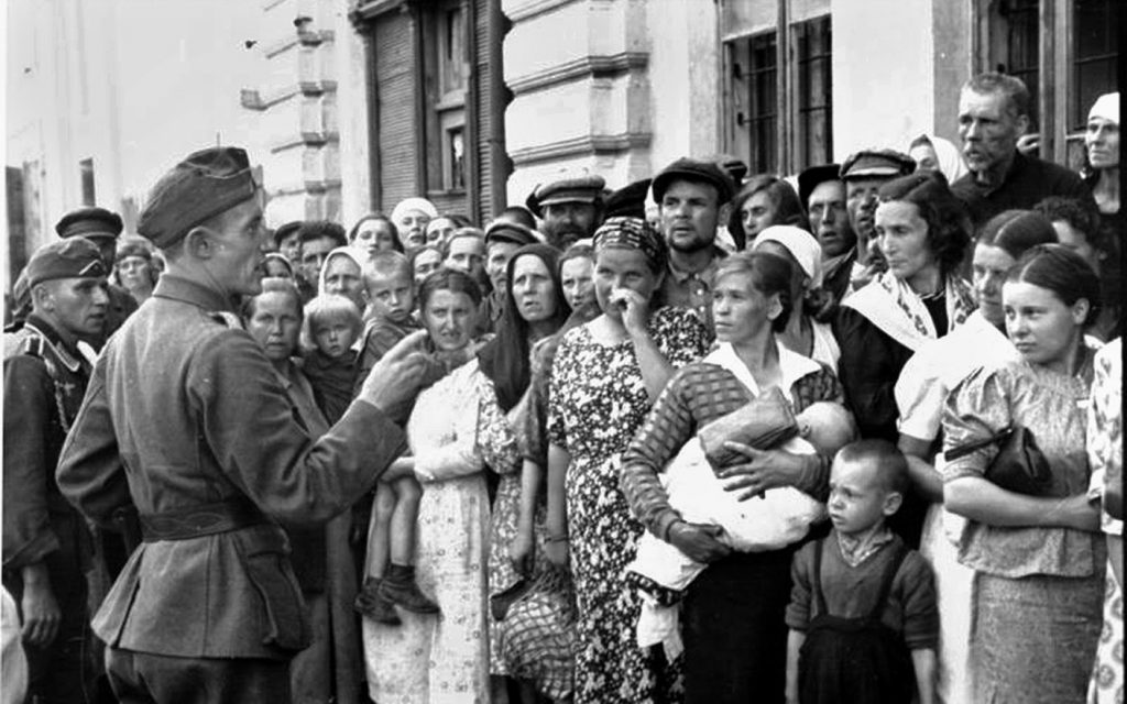 A German soldier tells a fearful crowd of civilians in Mogilev, Belorussia, that they will be relocated to a ghetto, July 1941. Einsatzgruppe D wiped out nearly all the Jews in Mogilev. 
