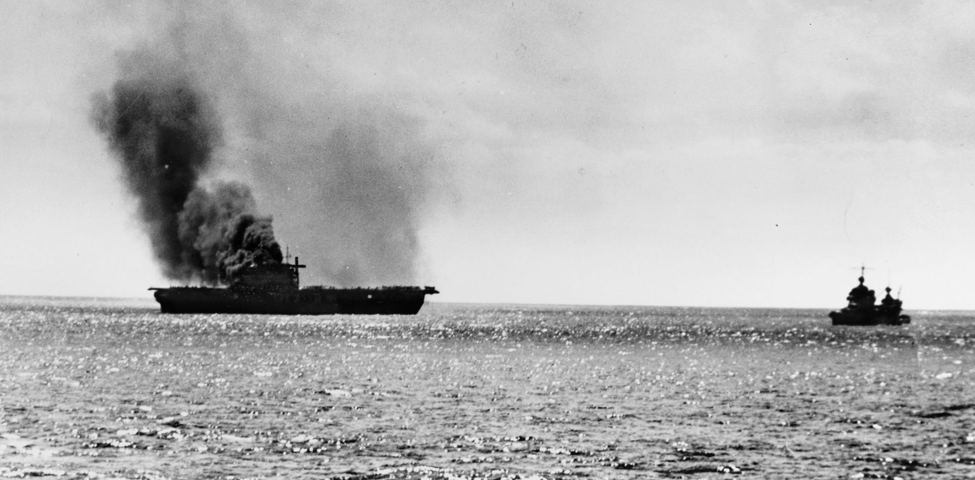 Smoke pours from the fatally damaged carrier USS Yorktown, June 6, 1942, as another ship moves in to effect rescue operations. Gwin also assisted in trying to save the ship and her crew, managing to pull more than 100 sailors from the water.