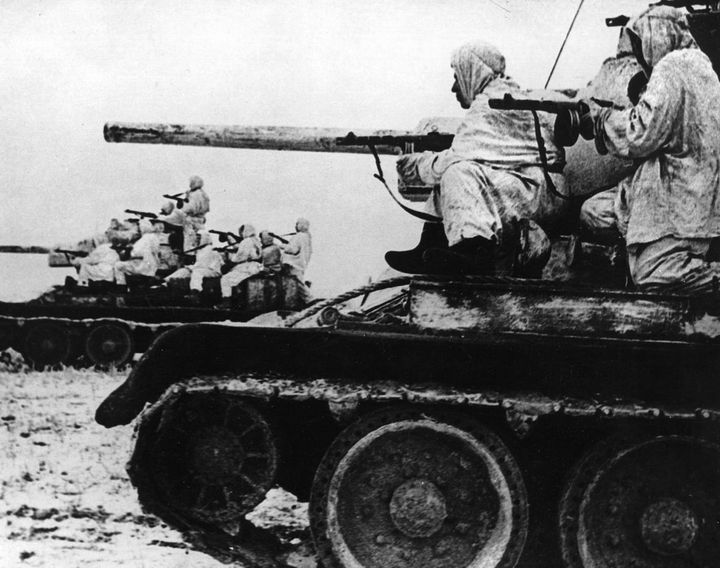 Russian tanks piled with soldiers thunder across the frozen landscape. It was not uncommon for Soviet commanders to flesh out their ranks with new recruits from liberated areas. 