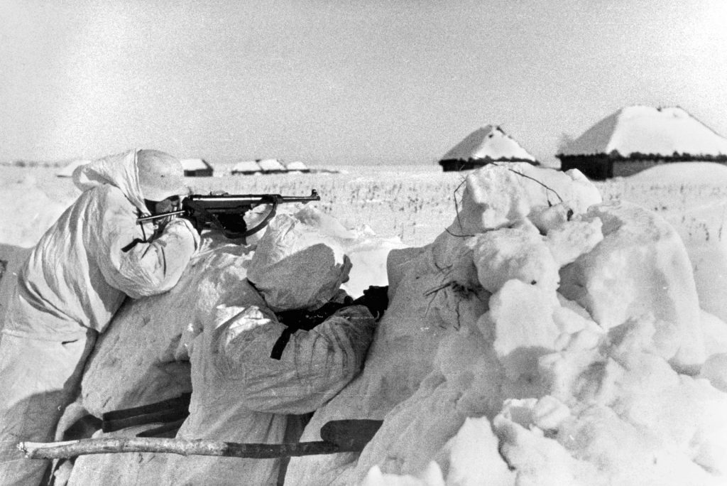 German soldiers in winter  camouflage defend their lines against oncoming Russians.