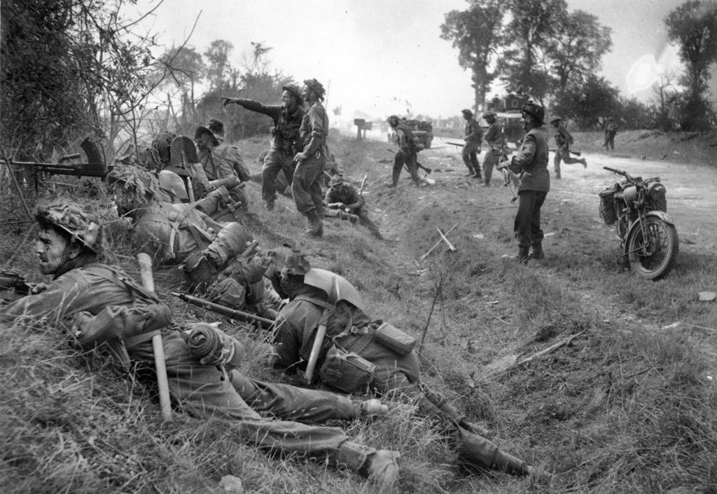 Taking cover in a ditch near the French town of Cagny, July 19, 1944—the second day of Operation Goodwood, the drive on Caen—soldiers of the 1st Battalion, Welsh Guards, prepare to move out. 