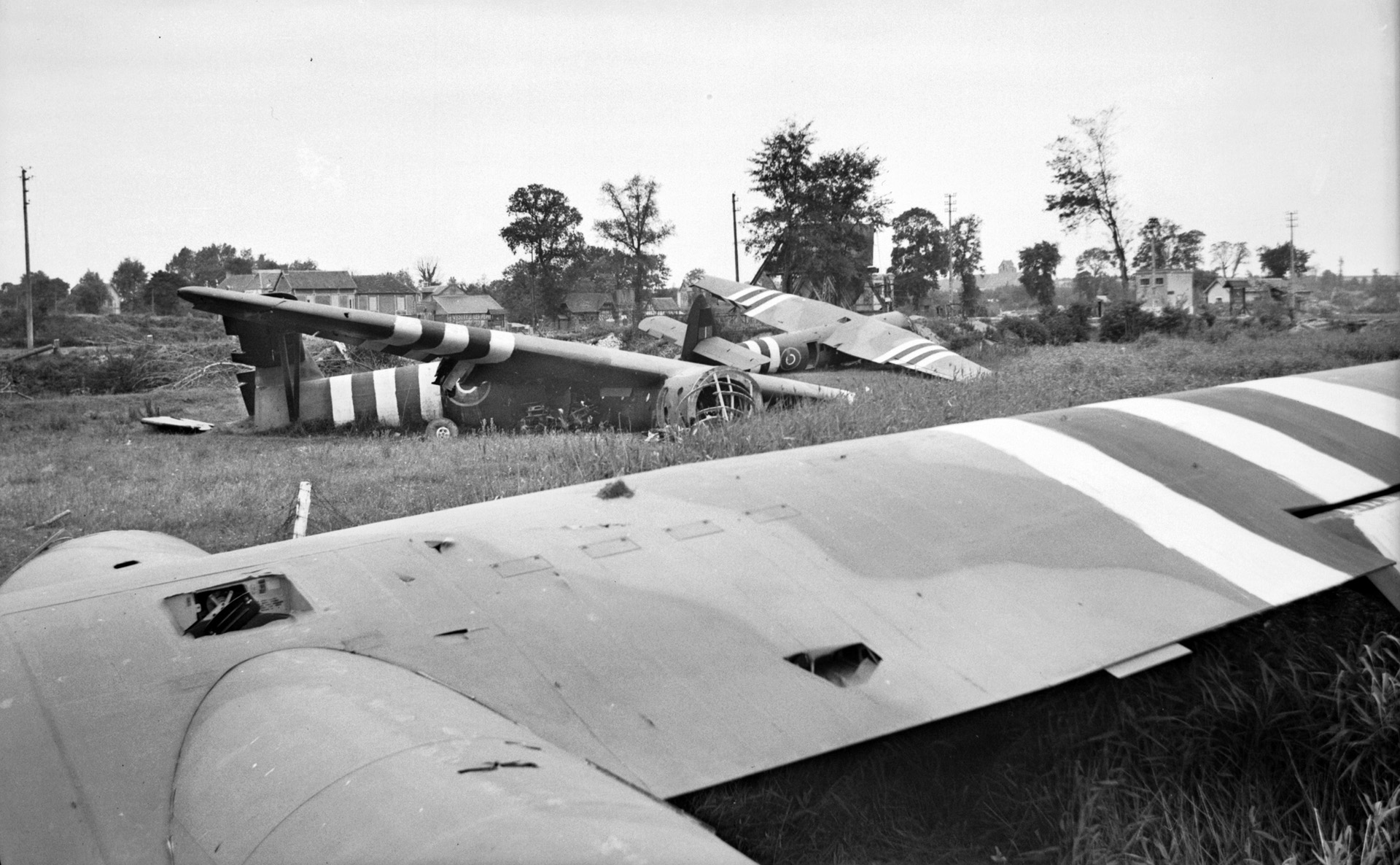 The wreckage of Horsa gliders litter a field near the Caen Canal Bridge. The impact of the landing ripped some of the men from their safety harnesses and hurled them through the cockpit window of the glider.