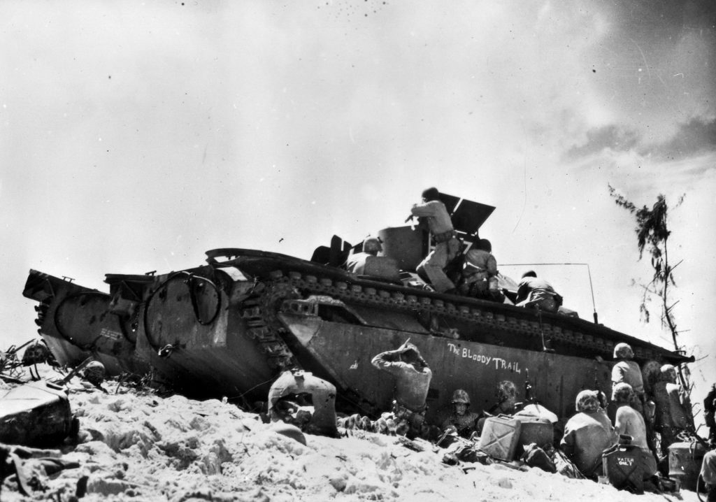 On Peleliu, a member of the 1st Marine Division fires at the enemy over the turret of an LVT while other Marines take cover before advancing. Some historians believe the bloody battle was unnecessary to the American’s Pacific Theater strategy. 