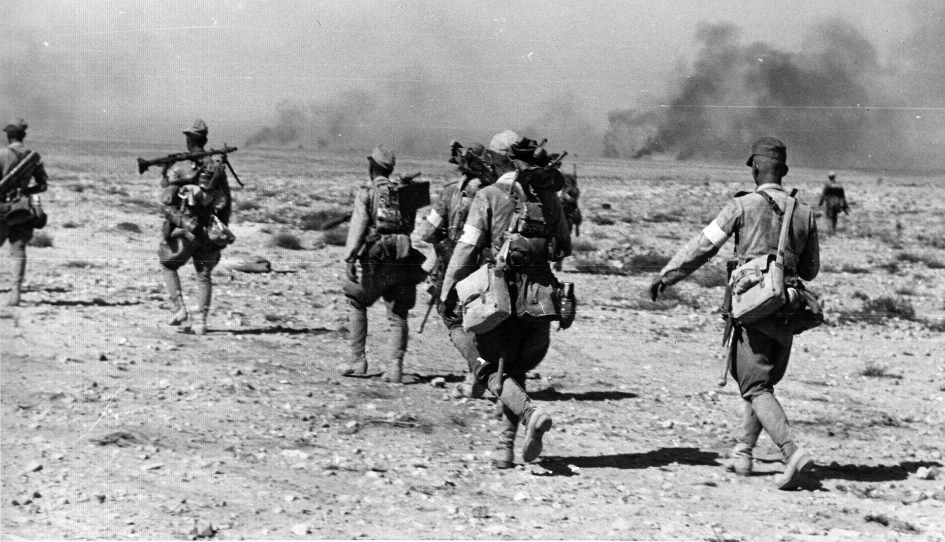 Axis troops march across a bleak North African landscape. Searing heat, freezing cold, biting flies, and a lack of cover and concealment made fighting in the forbidding terrain a hell for both armies.