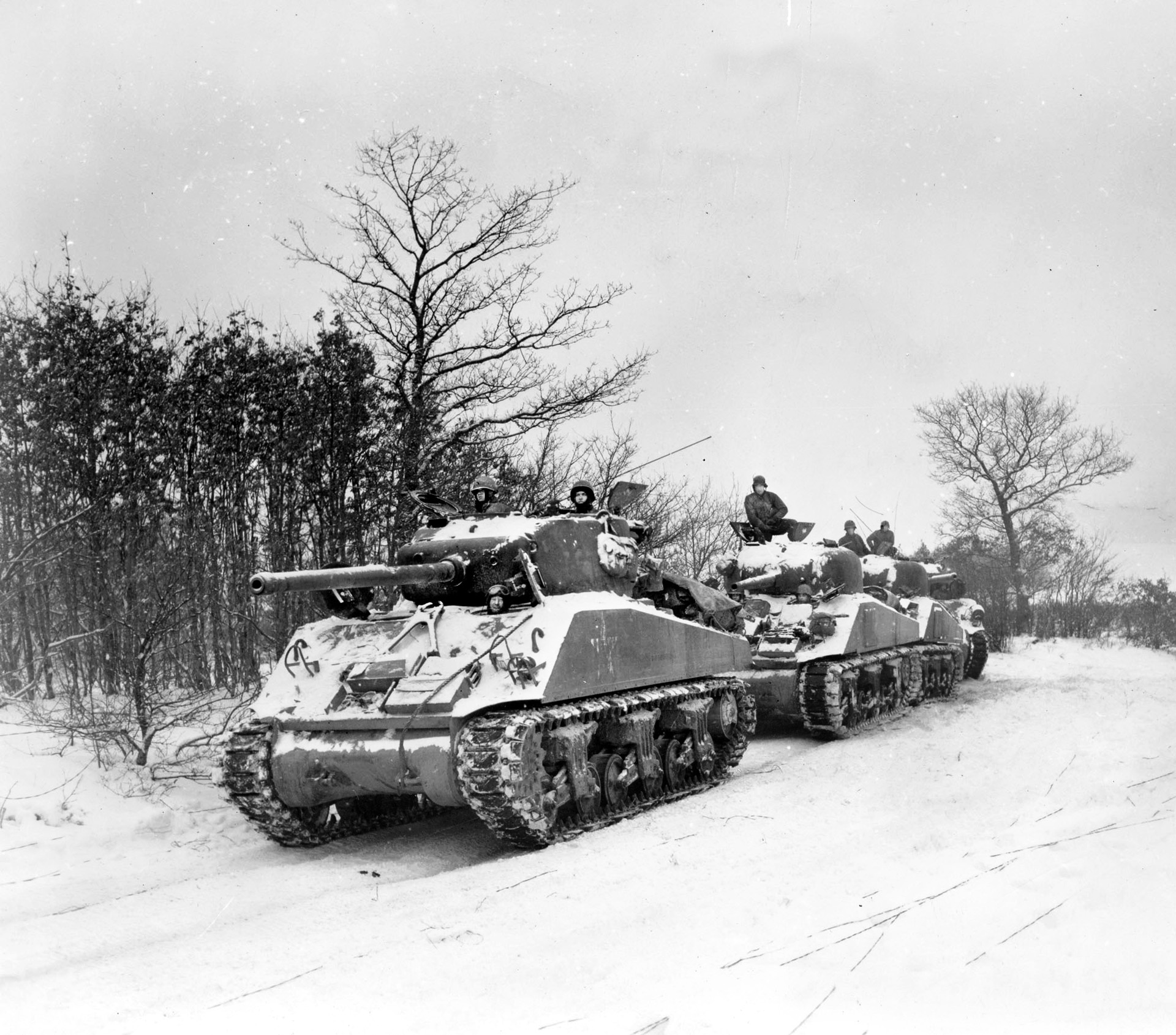 Four M-4 Sherman tanks with high-velocity 76mm guns prepare to roll toward the enemy along a Luxembourg road.