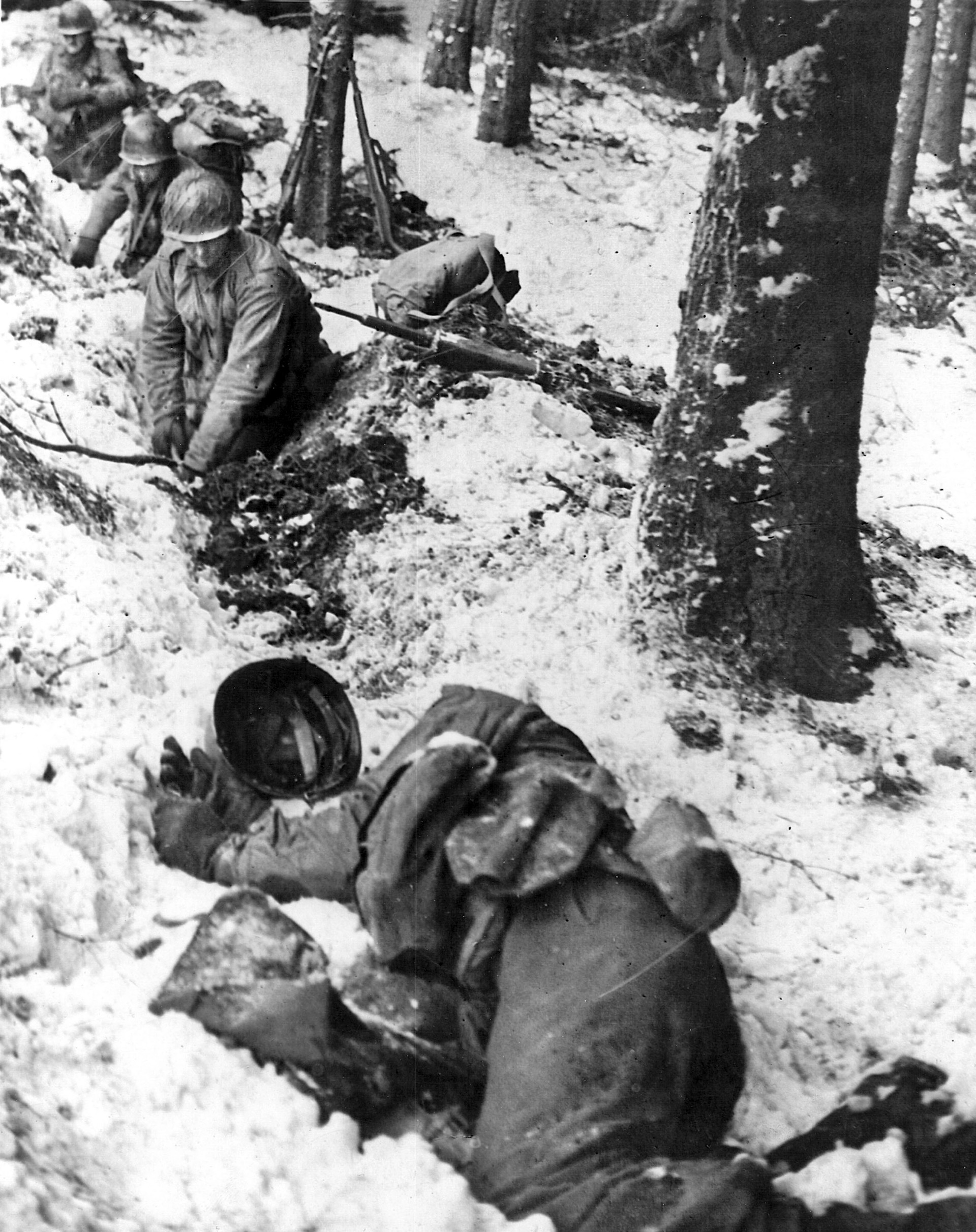 Despite the frigid cold and frozen ground, men of the 28th Infantry Division’s 110th Infantry Division hurriedly dig fighting positions in a ditch along a road in anticipation of an enemy attack.
