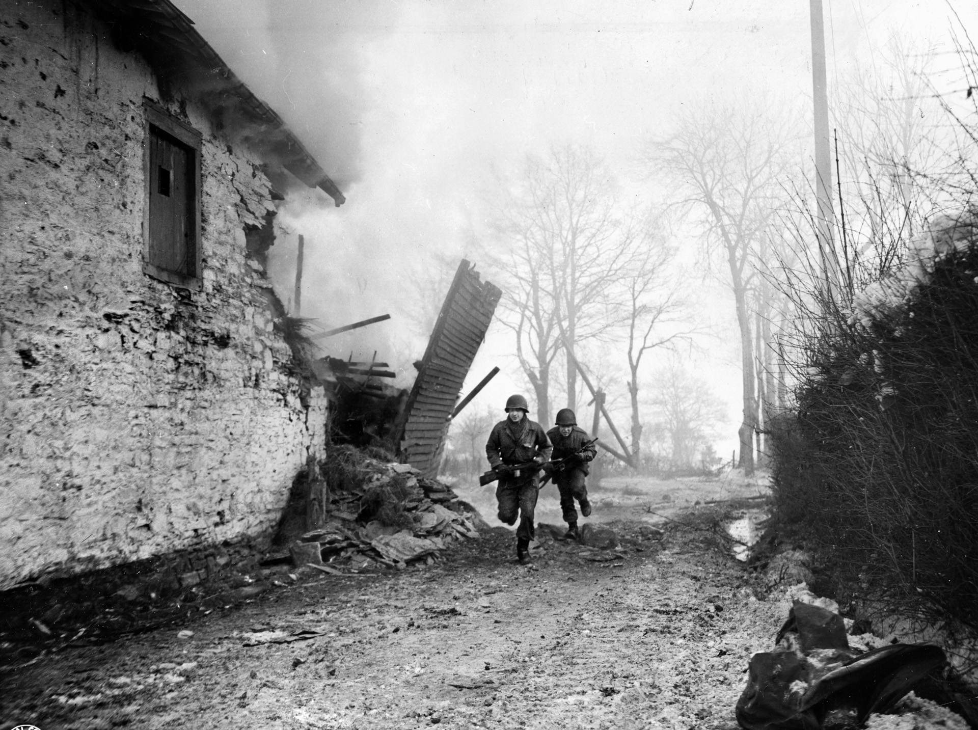 Two GIs run for cover during the Battle of the Bulge. The Nazis initiated their Ardennes Offensive in December 1944, hoping to cross the River Meuse and advance to the port of Antwerp, Belgium, splitting Allied forces in two. Hitler authorized Operation Nordwind two weeks after the Ardennes Offensive was launched in an attempt to exploit gains made to the north as the Allies shifted troops and military assets in response to the Ardennes threat. The stand at Hatten was critical in wresting the initiative away from the Germans.