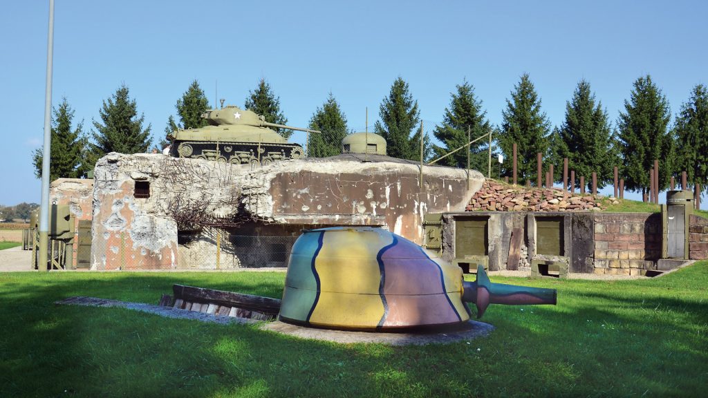 Casemate Esch (One), east of the village of Hatten, one of the fortifications of the Maginot Line that was the scene of heavy combat in early 1945, remains as a memorial to its American defenders. An M4 Sherman tank rests atop the fortification and is a focal point of the museum and memorial today.