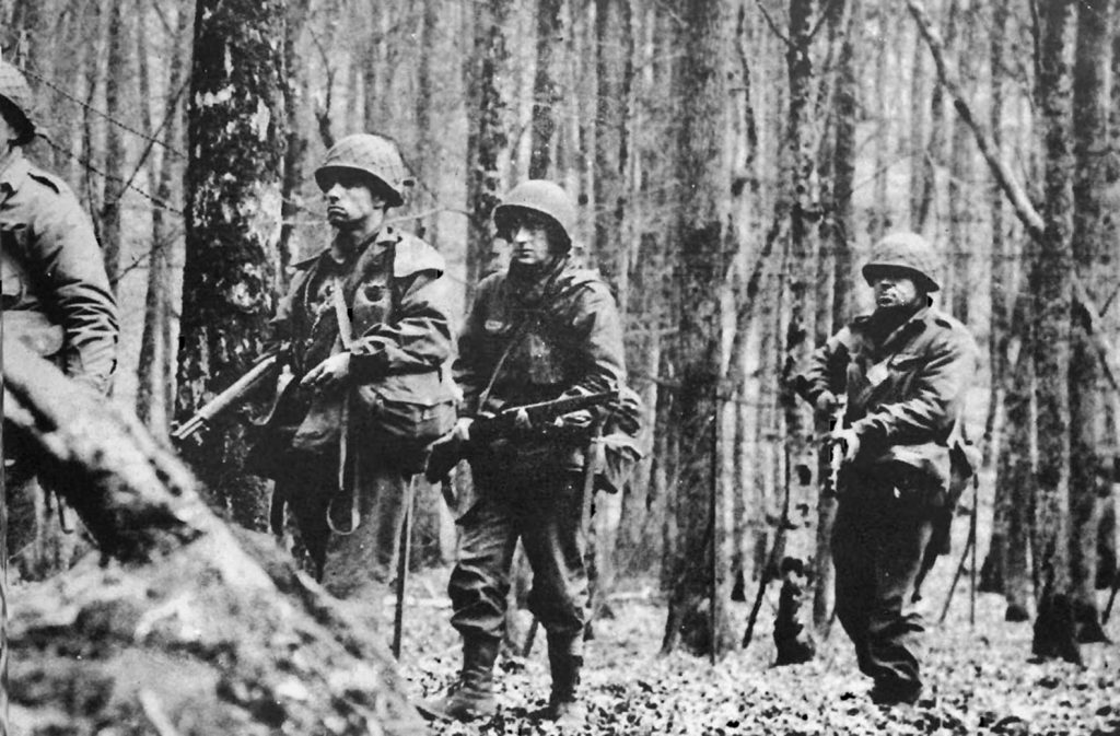 American soldiers of the 42nd Infantry Division patrol a heavily wooded area in France. The troops of the 42nd took heavy casualties in the defense of Hatten during Operation Nordwind.