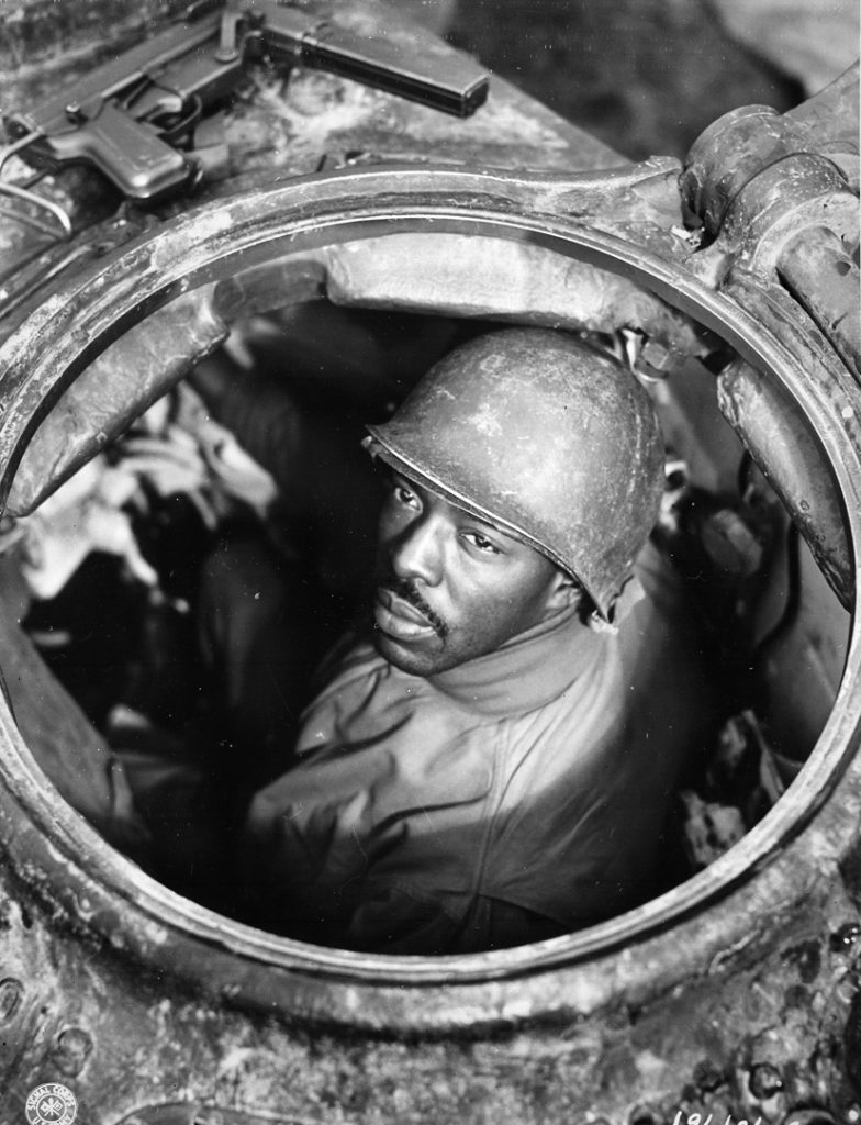 Corporal Carlton Chapman of the U.S. 761st Tank Battalion peers through the hatch of an M4 Sherman tank in the vicinity of Nancy, France. His M3, popular with tankers, is visible at the top of this photo from November 5, 1944. 