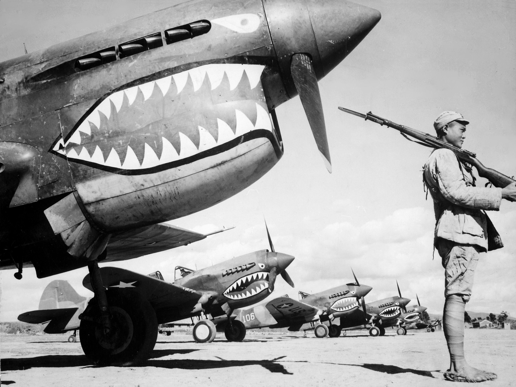 A Chinese soldier stands guard in front of P-40 Warhawk fighters of the AVG, at one of several airfields in China around 1942. 