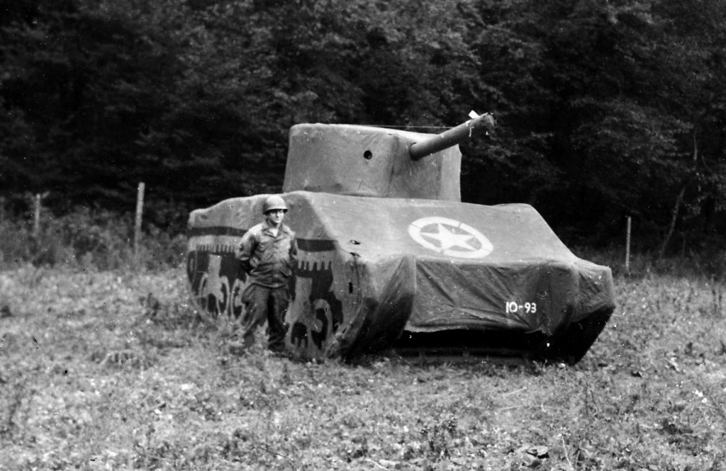 An American soldier stands guard beside a tank made entirely of rubber but bearing a strong resemblance to a U.S. M4 Sherman medium tank. 