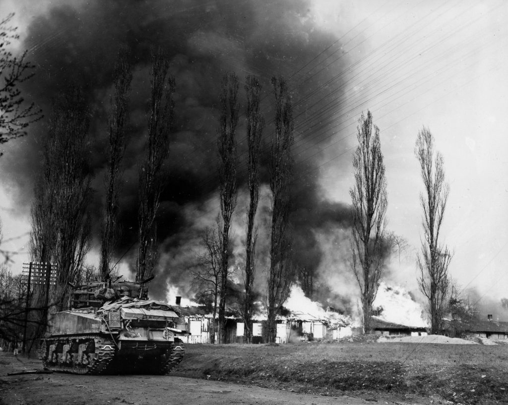 An American Sherman tank fires on a building near Aschaffenberg where German snipers are suspected of hiding.