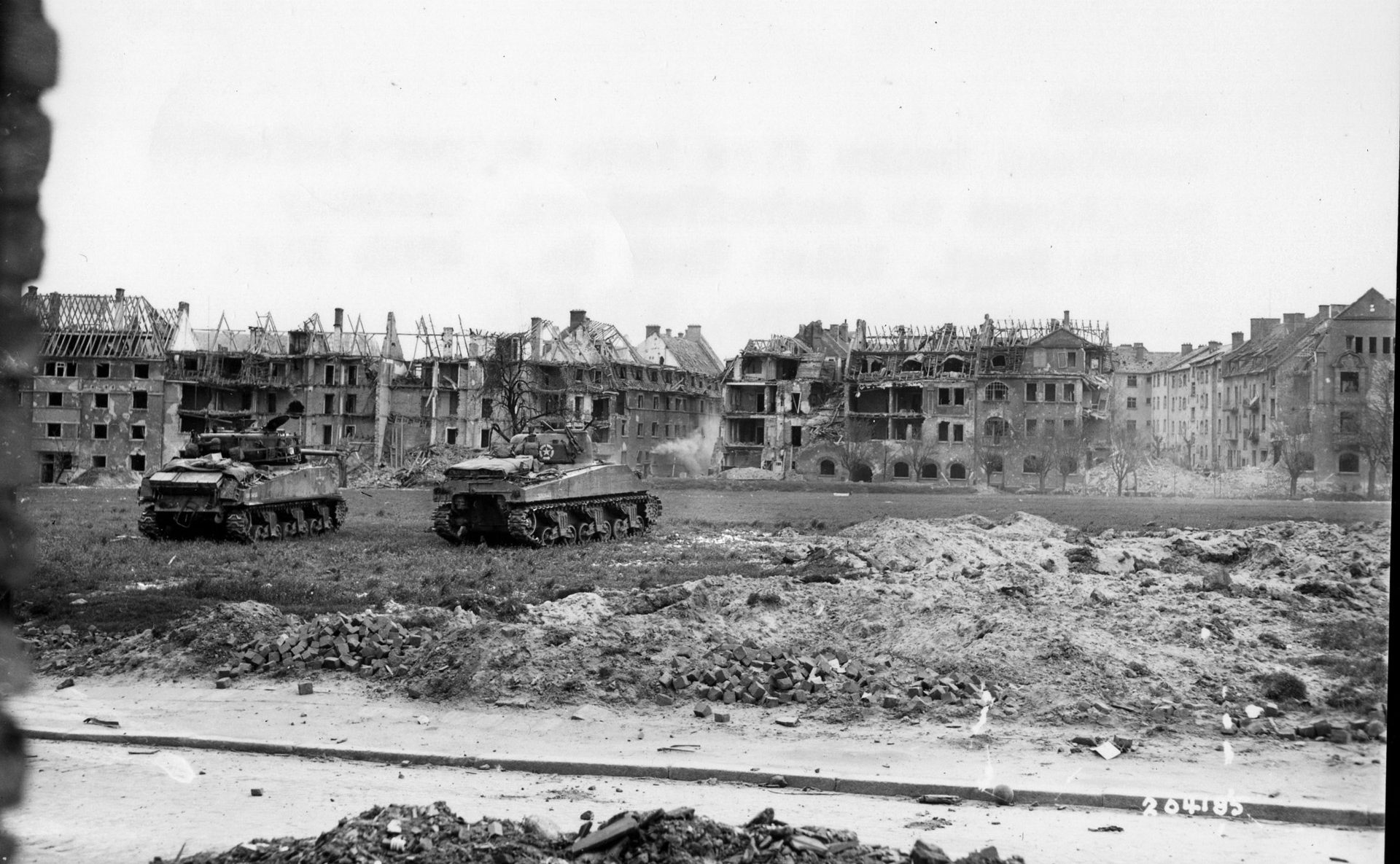 Sherman tanks train their guns on sniper positions at Aschaffenberg. German snipers were capable of holding up large formations of American troops unable to leave cover. 