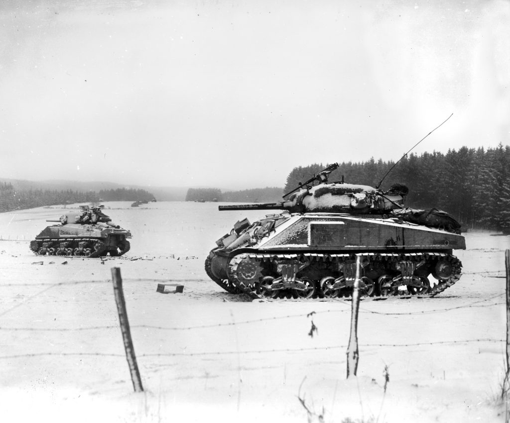A pair of M4 Shermans of the 35th Tank Battalion bivouac southwest of Bastogne near Vaux-les-Rosieres, just after Christmas, 1944. Even after reaching Bastogne, the Germans made efforts to cut the American corridor into the town. 