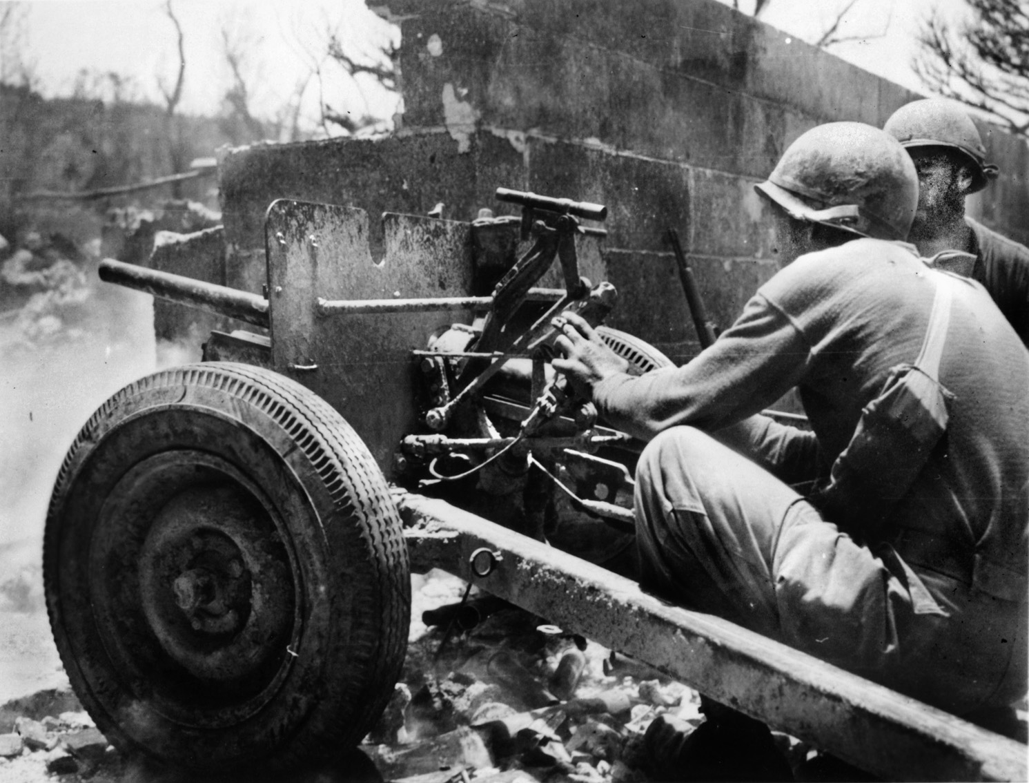 Partially sheltered by the ruins of a bombed out building, American soldiers of the 96th Infantry Division man a 37mm gun. 