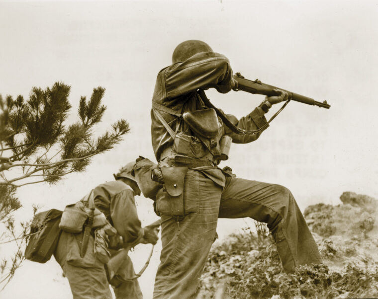 Two American soldiers of the 96th Infantry Division engage stubborn Japanese defenders on the island of Okinawa. One of them is seen firing his M-1 Garand rifle at a distant target, while the other is in the process of reloading his weapon. The bloody fight for Okinawa lasted 82 days.