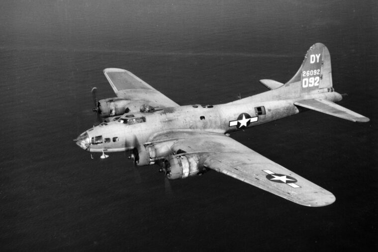 A Boeing B-17 Flying Fortress bomber flies over a body of water. Corporal Joseph Hartman survived a terrible ordeal following a mid-air collision aboard a B-17, which was followed by an incredible odyssey.
