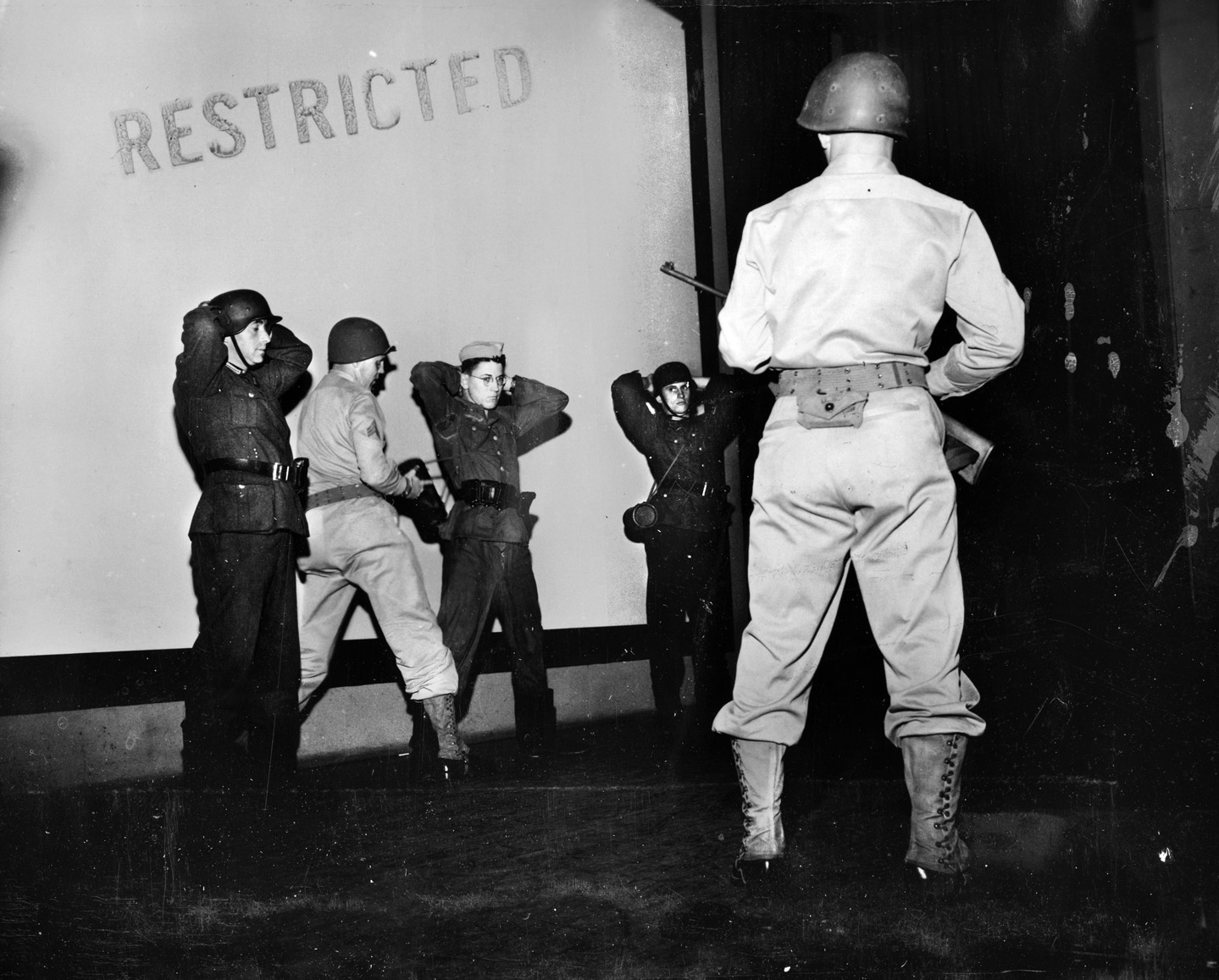 During a demonstration for Army personnel, a team of interrogators from Camp Ritchie demonstrates the proper method for searching prisoners of war.  Three members of the interrogation team are wearing German uniforms.