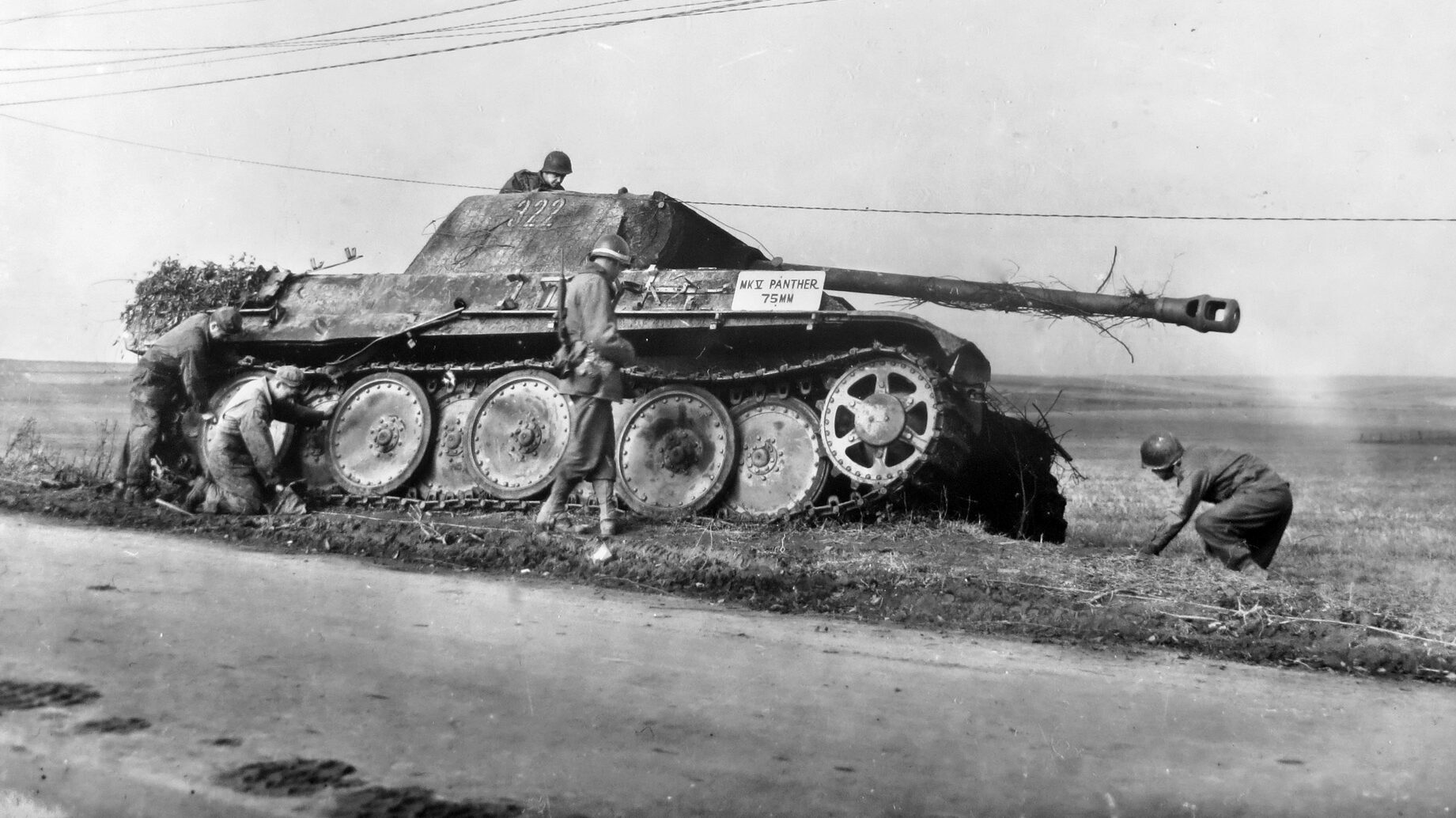 GIs inspect this Panther tank of Panzer Brigade 106, disabled during the Battle of Mairy. A sign has been placed on the tank to familiarize passing troops. 