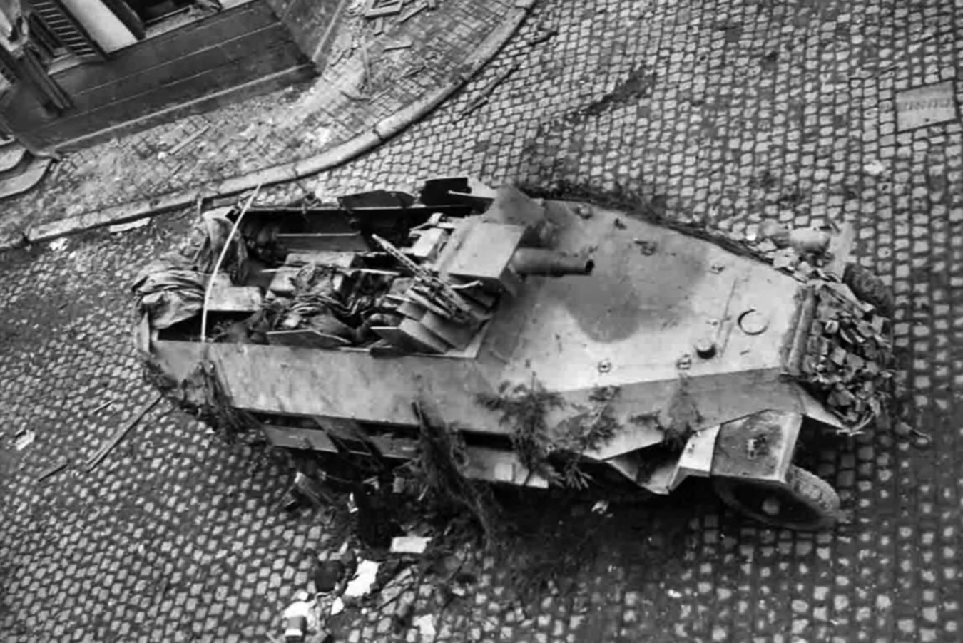 A German halftrack lies knocked out in the middle of a French village after falling victim to fire from American troops. The halftrack mounts a 75mm gun used for close infantry support and is deadly in street-to-street fighting.