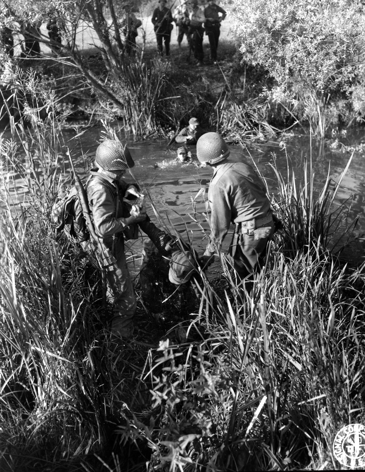 A surrendering German slogs his way out of a creek. After the battle, German soldiers attempted to escape the area in small groups, which led to scattered firefights.